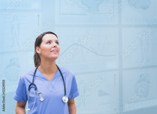 Photo: Nurse looking up against blue digital background Nurse looking up against blue digital background