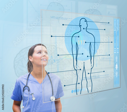 Photo: Nurse looking up to screen showing human form Nurse looking up to screen showing human form
