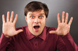 Young man with astonished expression and hands up