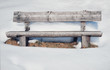 Old rustic wooden bench surrounded by lots of snow