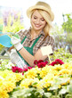 Smiling young woman watering flowers in the flowers market
