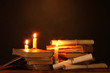 Foto: Pile of old books with candle and scroll in dark Pile of old books with candle and scroll in dark