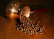 Coffee pot with coffee beans on brown wooden background