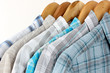 Photo: Shirts with ties on wooden hangers on light background Shirts with ties on wooden hangers on light background