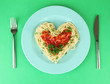 Cooked spaghetti carefully arranged in  heart shape and topped