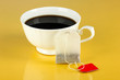 Cup of tea with tea bag on yellow background