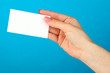 Foto: Female hand holding business card, on color background Female hand holding business card, on color background