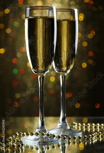 Photo: Two glasses of champagne on bright background with lights Two glasses of champagne on bright background with lights