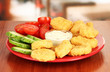 Fried chicken nuggets with vegetables and sauce on table in