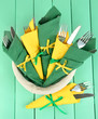 Forks and knives wrapped in green and yellow paper napkins,