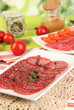 Photo: Tasty salami on plates on wooden table on natural background Tasty salami on plates on wooden table on natural background
