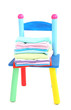 Foto: Small and colorful chair with baby clothes isolated on white Small and colorful chair with baby clothes isolated on white