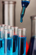 Photo: Laboratory pipette with drop of color liquid over glass test Laboratory pipette with drop of color liquid over glass test