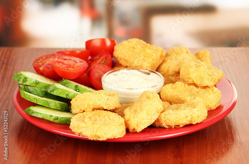 Photo: Fried chicken nuggets with vegetables and sauce on table in Fried chicken nuggets with vegetables and sauce on table in