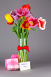 Beautiful tulips in bouquet with gifts and note