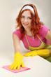 Young housewife cleaning up table at home on grey background