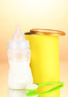 Bottle with milk and food for babies on beige background