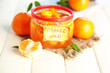 Orange jam with zest and tangerines, on white wooden table
