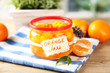 Orange jam with zest and tangerines, on wooden table