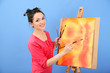 Foto: Beautiful young woman painter at work, on color background Beautiful young woman painter at work, on color background