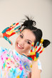 Young pretty painter with hands in paint, on gray background