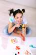 Young pretty painter with hands in paint, on gray background