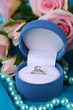 Rose and engagement ring on blue cloth