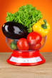 Fresh vegetables in scales on table on orange background