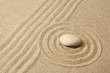 Zen garden with raked sand and round stone close up