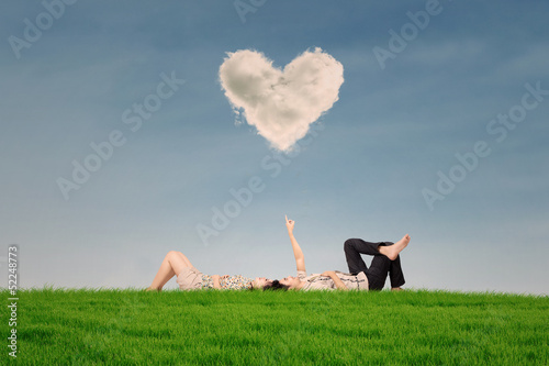 Photo: Couple enjoy holiday under heart cloud in park Couple enjoy holiday under heart cloud in park