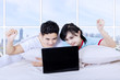 Couple winning looking at laptop in apartment