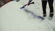 Car in snow, woman cleans snow from car