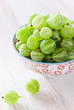 Green gooseberries in bowl, selective focus