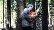 Man playing guitar in the woods leaning against tree/episode 1/