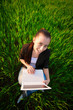 happy girl in a green field with a laptop. summer