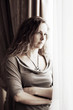 Foto: Sad beautiful woman looking out window Sad beautiful woman looking out window