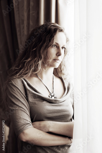 Photo: Sad beautiful woman looking out window Sad beautiful woman looking out window