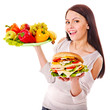 Woman choosing between fruit and hamburger.