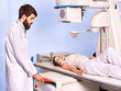 Patient  in x-ray room looking at doctor.