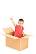 Foto: Smiling child in a paper box giving thumb up and looking at came Smiling child in a paper box giving thumb up and looking at came