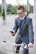 Portrait of young businessman on a bike using mobile phone