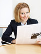 Business woman reads an article in the newspaper