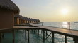 Island in ocean, overwater villas at the time sunset.
