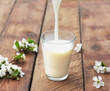 milk is flowing down to glass on wooden table
