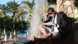 Young sad businessman reading documents in exotic resort