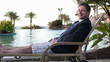Happy businessman relaxing on sunbed by the pool