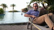 Video: Man video chat on laptop while sitting by the swimming pool Man video chat on laptop while sitting by the swimming pool