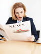 Woman reading newspaper is very surprised