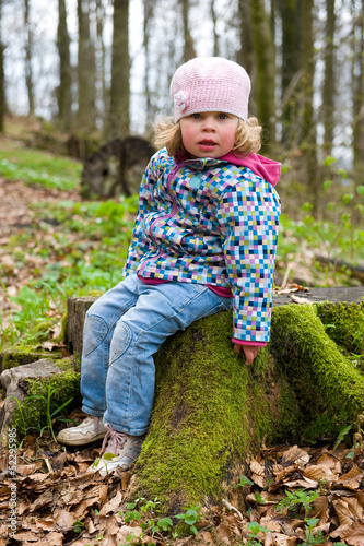 Photo: little girl is sitting on a stump little girl is sitting on a stump