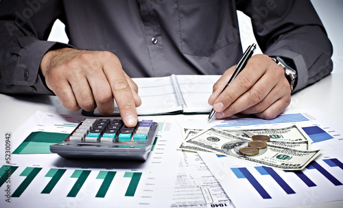 Photo: Hand with calculator and money. Hand with calculator and money.